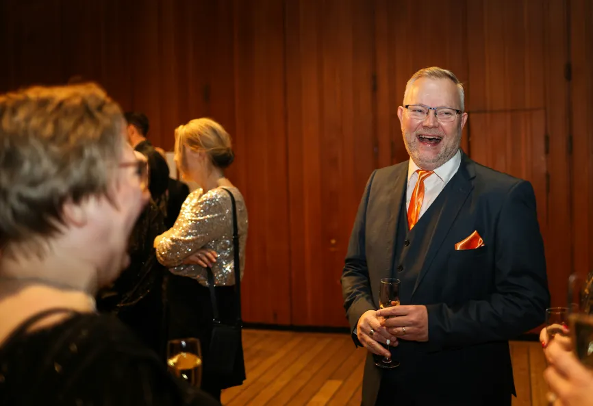 photo of a man in a suit laughing and drinking champagne